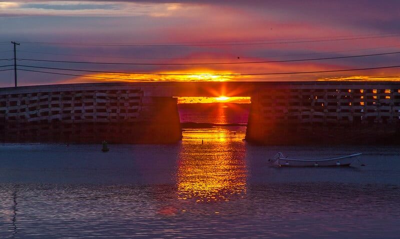 Cribstone Bridge at sunrise, with bright golden sun shining through the span of the bridge.