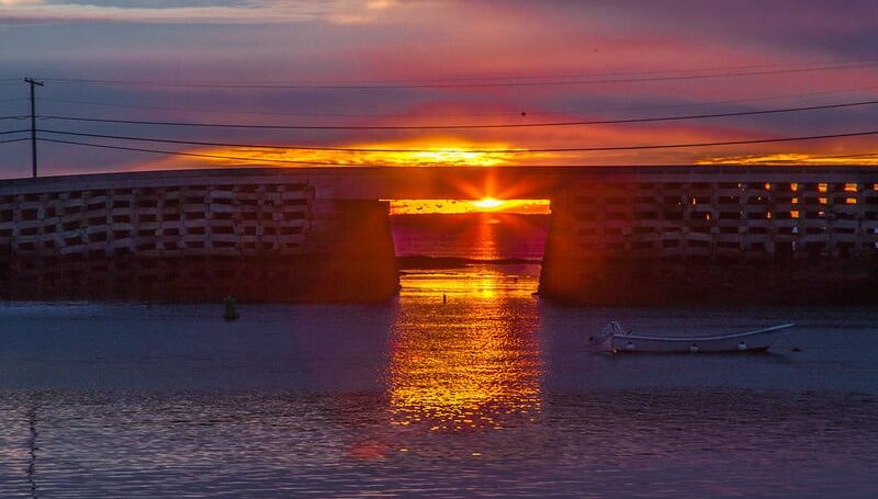 Cribstone Bridge at sunrise, with bright golden sun shining through the span of the bridge.