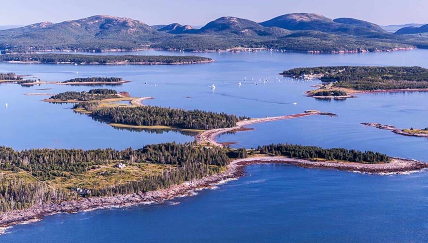 Aerial view of the Cranberry Islands with the hills of Acadia National Park in the background.