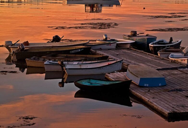 Dinghies tied to dock at sunset.