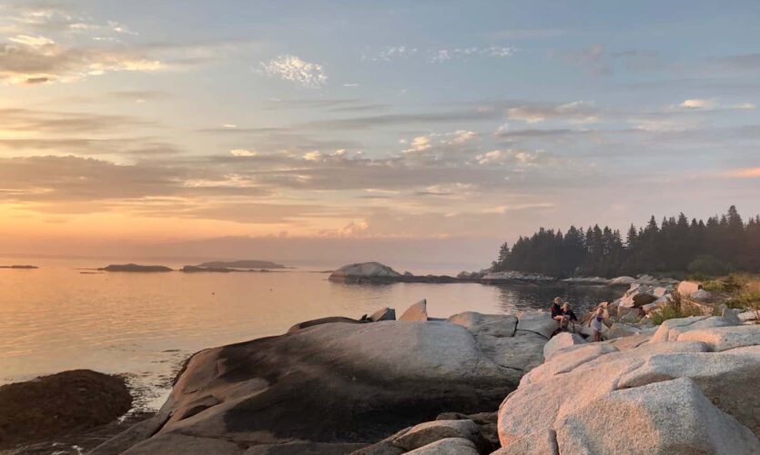 large boulders in foreground, glassy water, islands in the distance