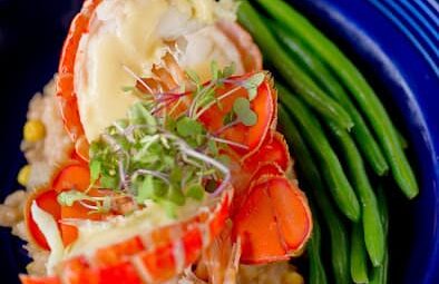 lobster split open on plate with green beans on the side
