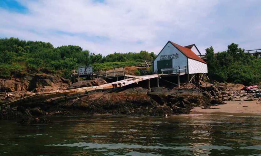 White building with wooden ramp leading down to the water on Seguin Island.
