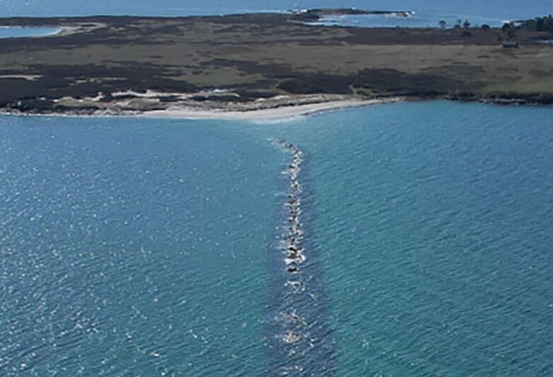 Aerial view of Richmond Island showing the breakwater, awash, heading straight out to the island.