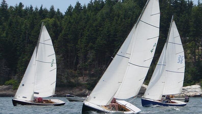 small one-design sailboats under main and jib