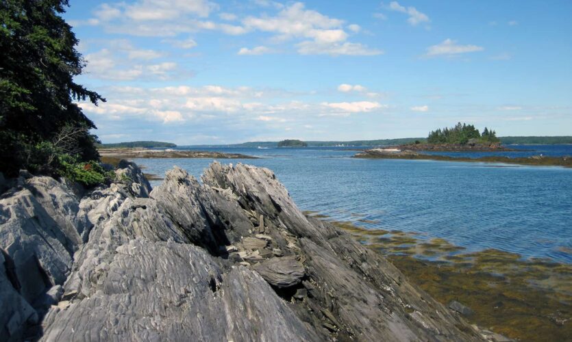 rocky shore in the foreground with islands in the middle distance and the mainland in the far distance