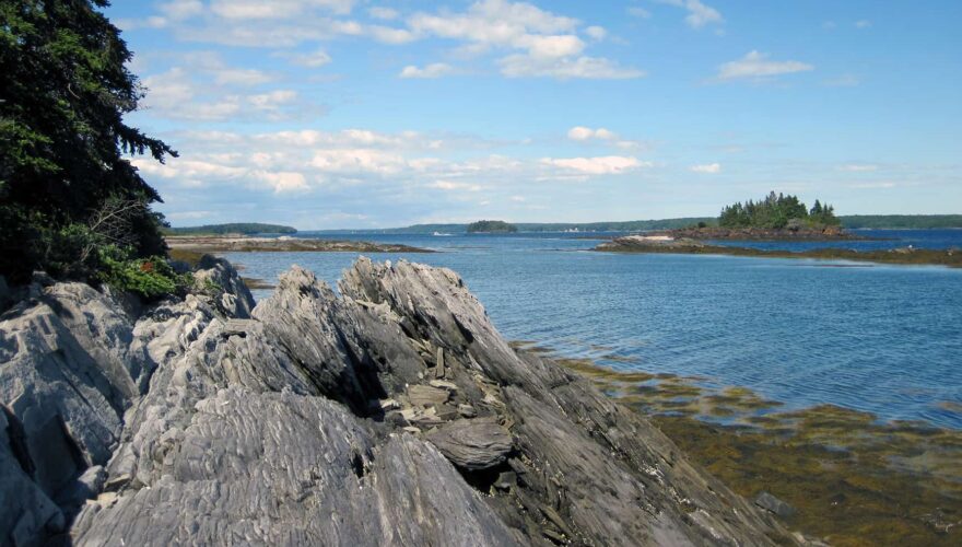 rocky shore in the foreground with islands in the middle distance and the mainland in the far distance